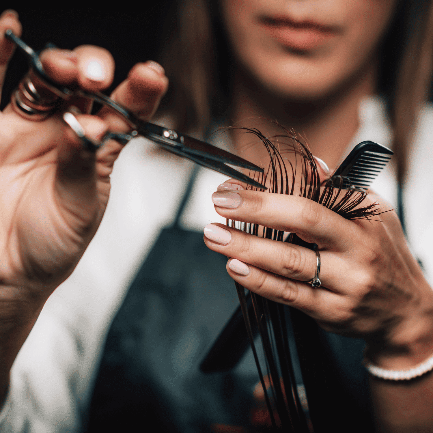 Hairdresser trimming hair with scissors and comb in hand.