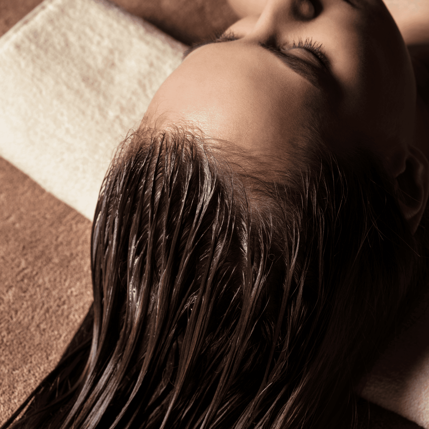 Moisturized hair during a spa treatment on a relaxed person, towel under head.